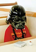 A sad kid wearing a Darth Vader helmet
