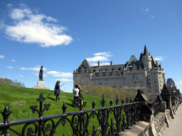Groundskeepers raking up stray grass on Parliament Hill, with Chateau Laurier in the background