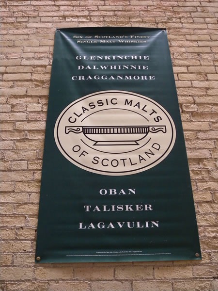 Banner on brick wall: "Classic Malts of Scotland: Glenkinchie, Dalwhinnie, Cragganmore, Oban, Talisker, Lagavulin" 