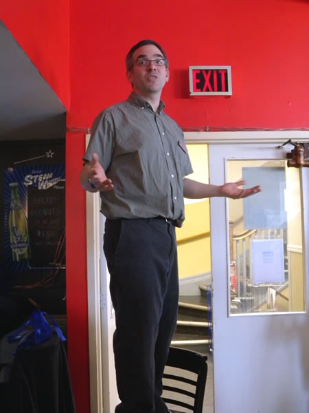 Greg Wilson, standing on a chair, addressing the students