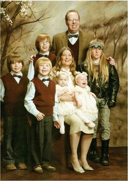 Family photo where everyone except one kid is dressed in their Sunday best; one kid us dressed like a biker/metal dude.