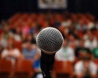 Photo: Microphone in foreground, auidence in background.