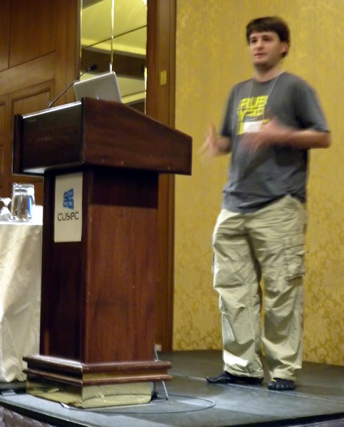 Matt Knox, standing at the lectern, delivering his keynote at CUSEC