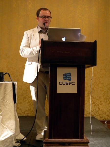 Pete Forde, standing at the lectern, giving his keynote at CUSEC 2010