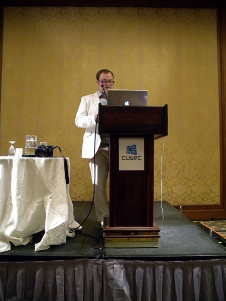 Pete Forde, standing at the lectern, giving his keynote at CUSEC 2010