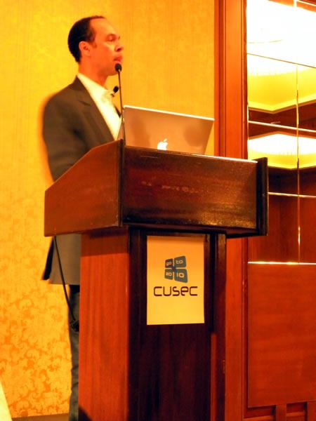 Reg Braithwaite, standing at the lectern, giving his keynote at CUSEC 2010