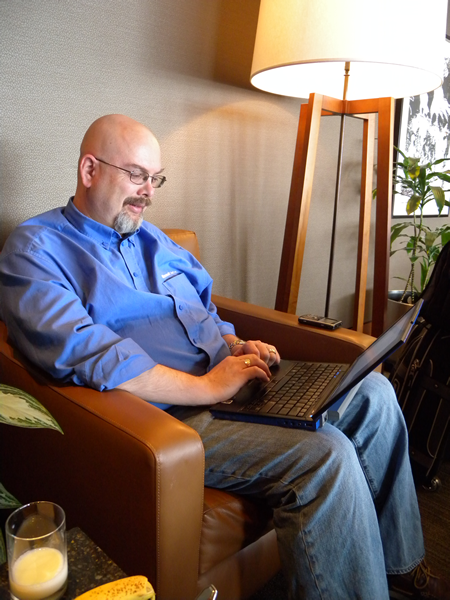 Damir Bersinic working on his laptop in an easy chair in Vancouver airport's Air Canada lounge