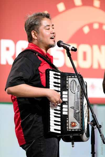 Joey deVilla playing accordion in front of the RailsConf logo