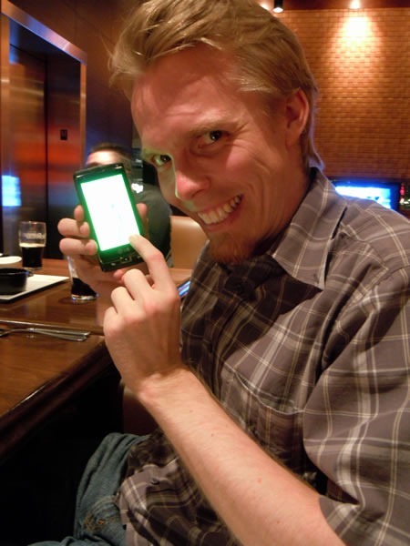 Morten Rand-Hendriksen smiles maniacally as he holds a Windows Phone 7 device