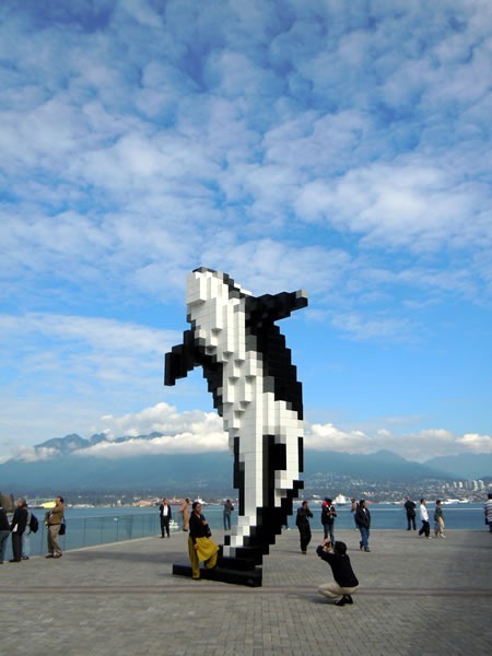 People posing by "Digital Orca", a pixelated killer whale statue