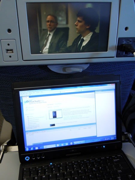 "The Social Network" playing on in-flight entertainment system while I work on my laptop, with Visual Studio Express for Phone onscreen
