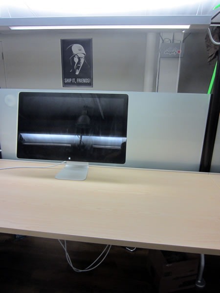 A desk that is empty except for an Apple monitor