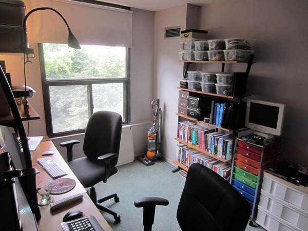 Joey's home office as seen from the desks, showing a windows overlooking treetops and the bookshelves and organizers