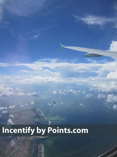 "Incentify by Points.com": View of an airplane's wing, sky, oceans and islands from the window seat