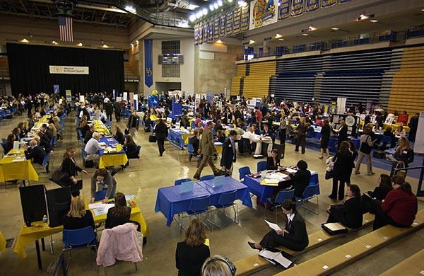 A traditional job fair: a gym with stations made of folding tables with prospective employers at each one. It looks like bureaucratic Hell on Earth.