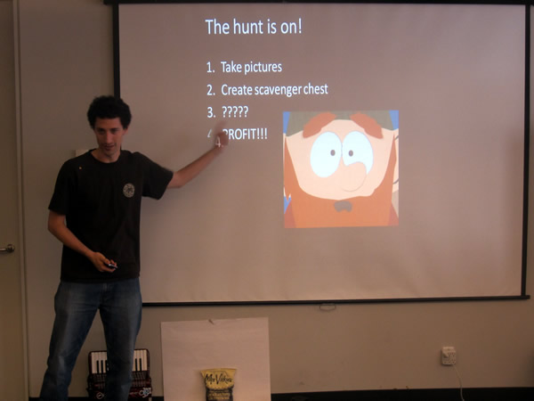 A hakcer at HackVan 2011 presenting his app: "1. Take pictures. 2. Create scavenger chest. 3. ???? 4. PROFIT!!!"