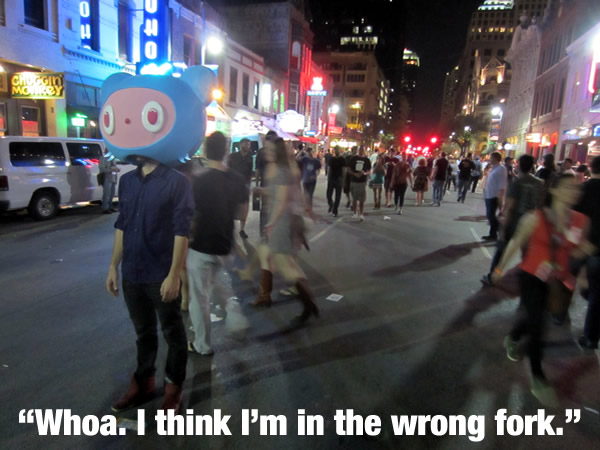 Guy wearing a giant Octocat head standing in the middle of Austin's 6th street during South by Southwest