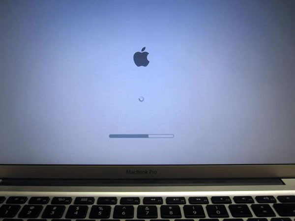 Photo: MacBook Pro screen, showing the OS X Yosemite progress bar a little past the halfway mark.