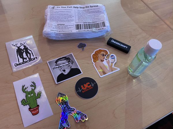 Photo: An assortment of Undercroft and security-related stickers, a packet of surgical masks, a small bottle of hand sanitizer, and an Undercroft-branded USB key.