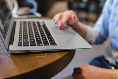 Photo: Woman’s hands typing on Mac laptop.