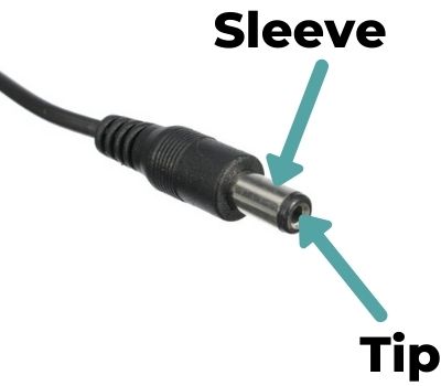 Close-up photo of a power adapter connector, with arrows pointing out the sleeve and tip.