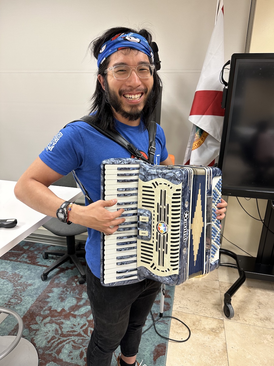Vincent Tang trying out my accordion, grinning widely.
